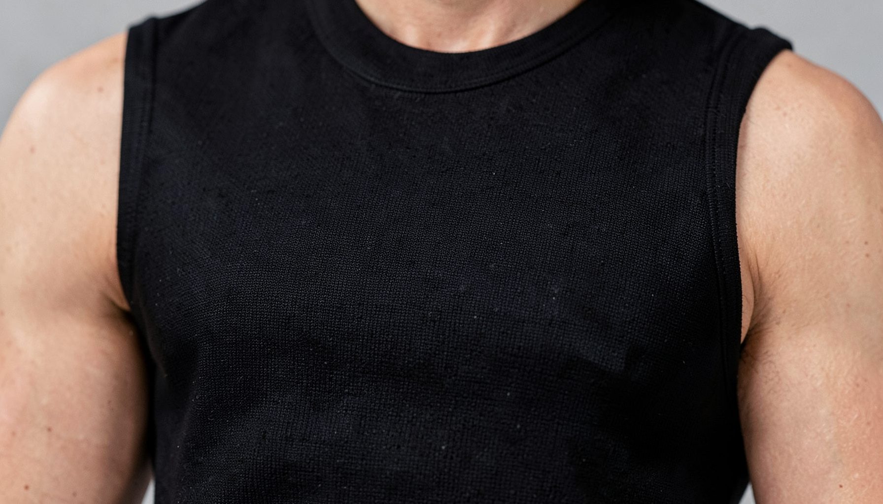 Sleeveless black compression vest for men, close-up on textured fabric with a subtle sheen