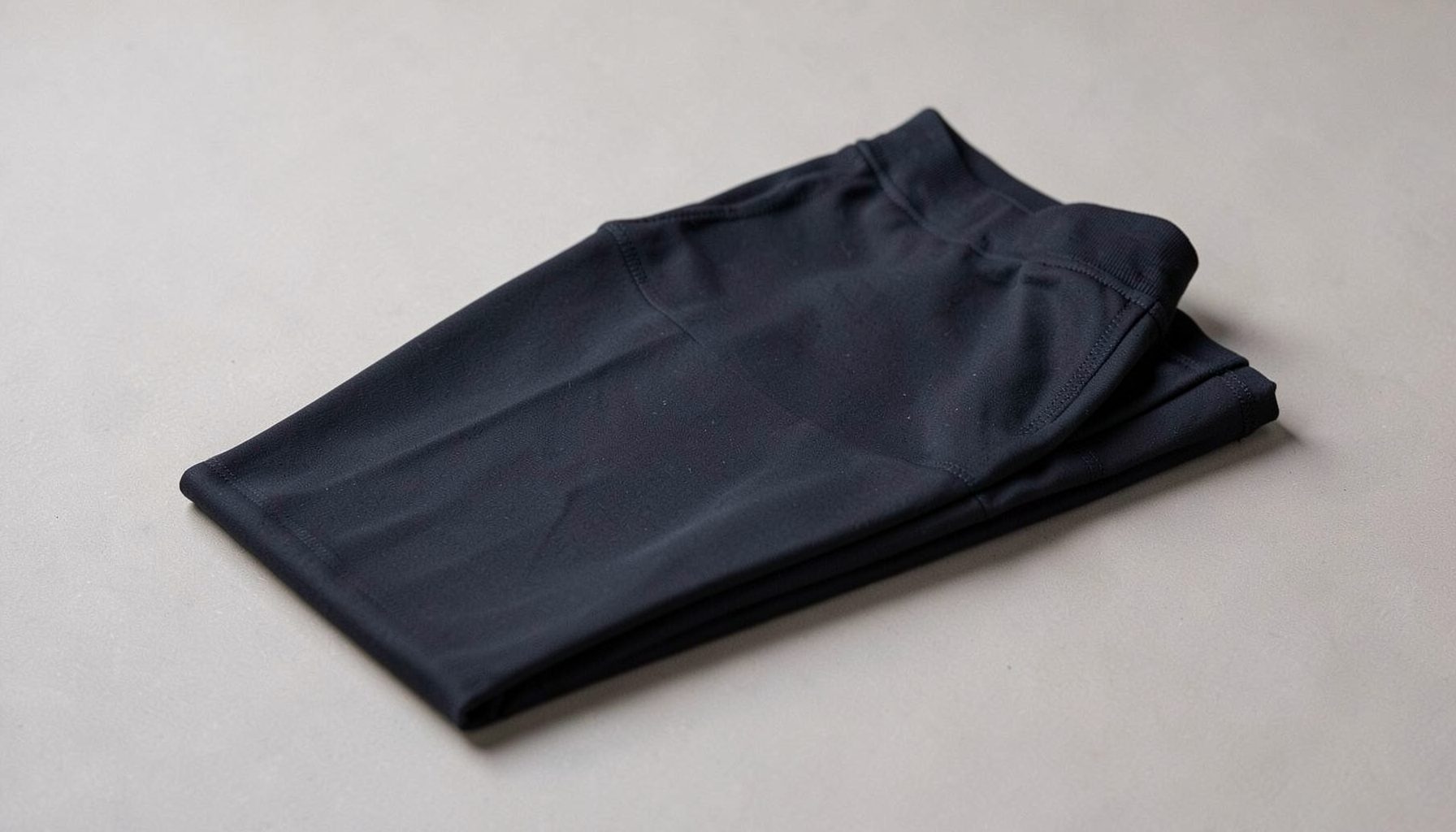 Folded dark navy athletic garment on a light gray surface, neutral mood